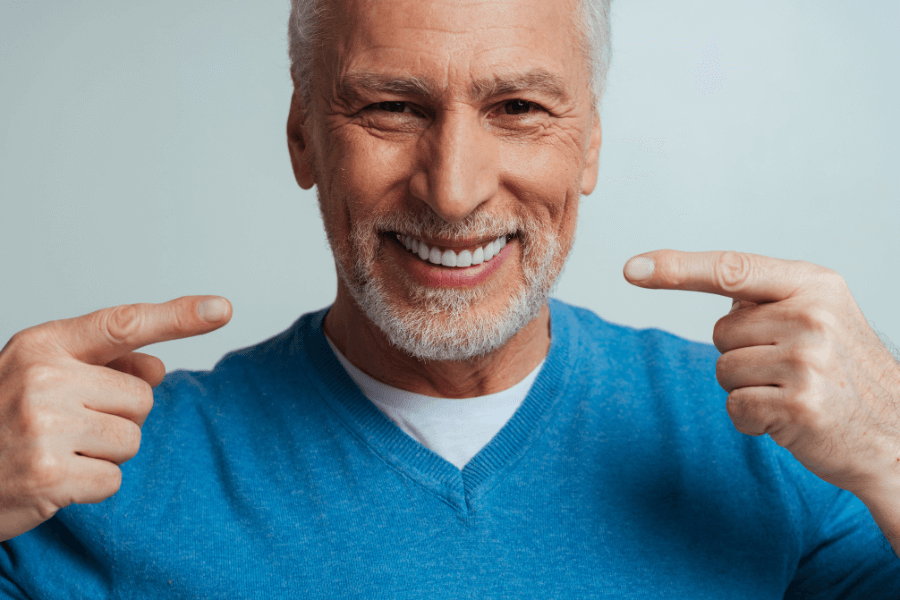 Homem branco idoso exibindo implante dentário